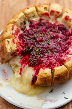 a cheesecake with cranberry sauce and herbs on top sits on a plate