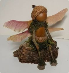 a figurine of a fairy sitting on top of a tree stump with wings