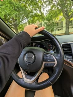 a person driving a car with their hands on the steering wheel and trees in the background