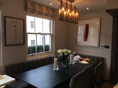 a dinning room table with candles and flowers in vases next to the window