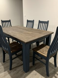 a wooden table with chairs around it in an empty room on the floor next to a white wall