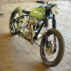 a green motorcycle parked on top of a brick road