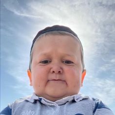 a little boy with an orange ear tag on his head looking up at the camera