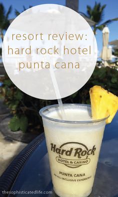 a drink with a straw in it sitting on top of a table next to a sign that says resort review hard rock hotel punta cana