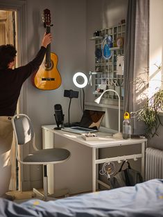 a man is playing an acoustic guitar in his bedroom