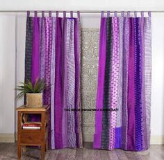 the purple curtains are hanging on the wall next to a small table with a potted plant