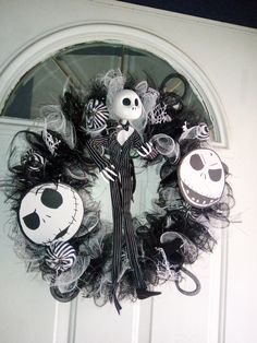 a wreath decorated with halloween decorations and skeleton faces on the front door to a house