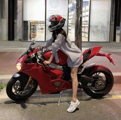 a woman sitting on top of a red motorcycle