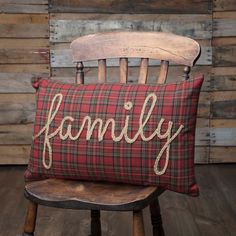 a chair with a pillow that says home and garden essentials family on it, sitting in front of a wooden wall