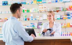 a man and woman standing in front of a counter at a drugshop talking to each other