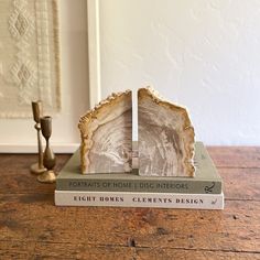 a bookend made out of two books sitting on top of a wooden table next to a candle holder