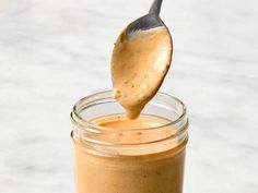 a spoon full of peanut butter on top of a jar