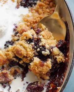 a close up of a spoon in a bowl of food with yogurt and blueberries