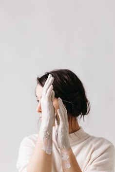 a woman in white gloves holding her hands up to her face