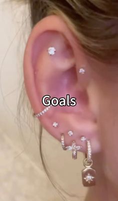 a woman wearing ear piercings with the words goals written in white letters on it