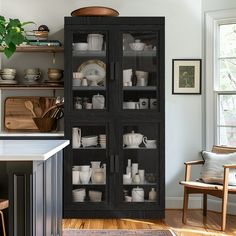 a black cabinet filled with white dishes in a living room next to a wooden chair