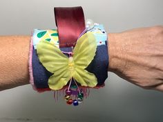 Fidget wrist/arm cuff provides touch sensory for children. Adults with Dementia, Alzheimers.  Velcro allows this to wrap around your wrist to keep in place. Undo the velcro to lay flat for a small lap pad. Can help calm anxiety by having different textures to fidget with.  Textures include: ribbon, button, beads, fabric butterfly, sequins  rayon  fringe, silicon band embossed polyester to rub. The backside is Dot polyester. Polyester batting in between layers of fabric. Other touch sensory fidget items available at MinniMaggie.etsy.com Machine wash and lay flat to dry. Textured Blankets, Adaptive Clothing, Fabric Butterfly, Baby Bottoms, Hook And Loop Tape, Arm Cuff, Wrist Cuffs, Alzheimers, Different Textures