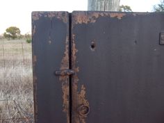 an old rusted metal door is in the middle of a field with dry grass