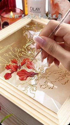 a woman is painting flowers on a glass tray with gold foil and watercolor pencils