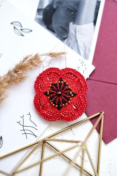 a red beaded brooch sitting on top of a table next to other items