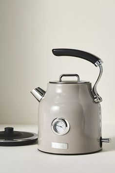 a silver tea kettle sitting on top of a white counter next to a black lid