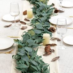 the table is set with candles and greenery