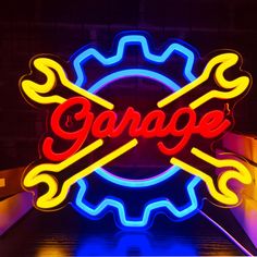 a large neon sign that says garage and two crossed wrenches on it's side