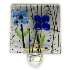 two blue flowers on a white background with black and green stems in the center, attached to a metal hook