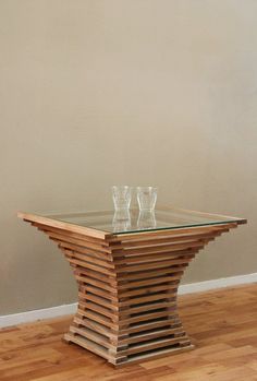 a wooden table with three glass vases sitting on it's top in front of a wall