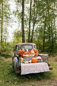 an old truck with pumpkins and gourds in the back