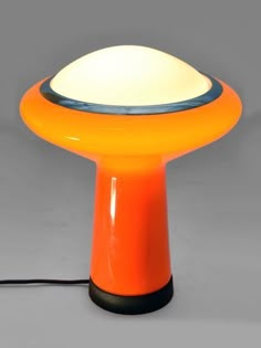 an orange table lamp sitting on top of a gray floor