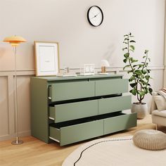 a living room with a clock on the wall next to a green chest of drawers