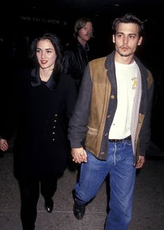 a man and woman walking down the street holding hands