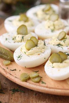 deviled eggs with pickles and dill on a wooden platter for appetizers