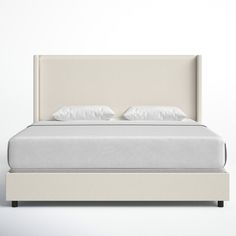 a bed with white sheets and pillows on it's headboard, in front of a wall