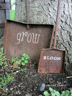 two rusty shovels sitting next to a tree with the word grow written on it