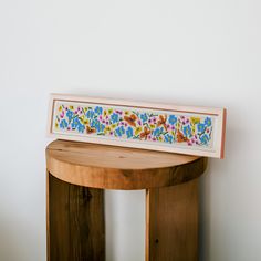 a wooden table topped with a painting on top of it's sideboard next to a white wall