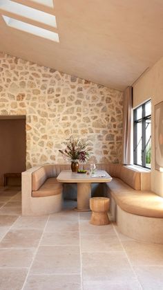 a room with stone walls and flooring, including a round table in the center