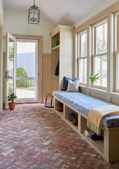 a brick floored entryway with a bench and potted plant in the corner