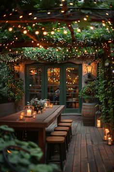 an outdoor dining area is lit up with lights and greenery on the roof, along with wooden tables surrounded by potted plants