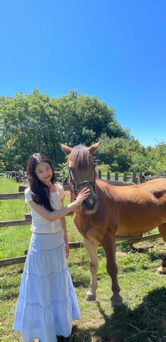 a woman standing next to a brown horse