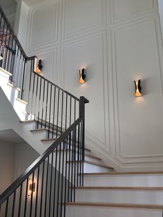 two lights on the wall next to a stair case in a house with white walls