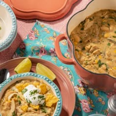 two bowls of soup are sitting on a table with other plates and utensils