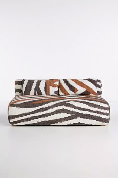 a brown and white striped purse sitting on top of a table next to a wall