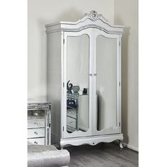 a white armoire with mirrored doors and drawers