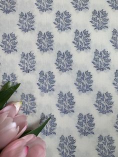 pink tulips are sitting in front of a blue and white wallpaper