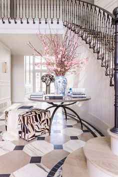 a vase with pink flowers sitting on top of a table next to a spiral staircase