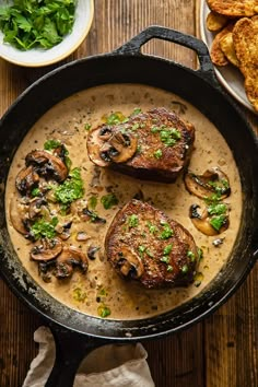 two steaks covered in mushroom sauce and garnished with parsley on the side