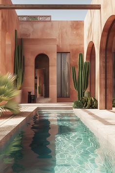 an indoor swimming pool surrounded by cactus and stone arches, with water running through it