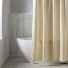 a white bathtub sitting next to a window in a bathroom with a shower curtain